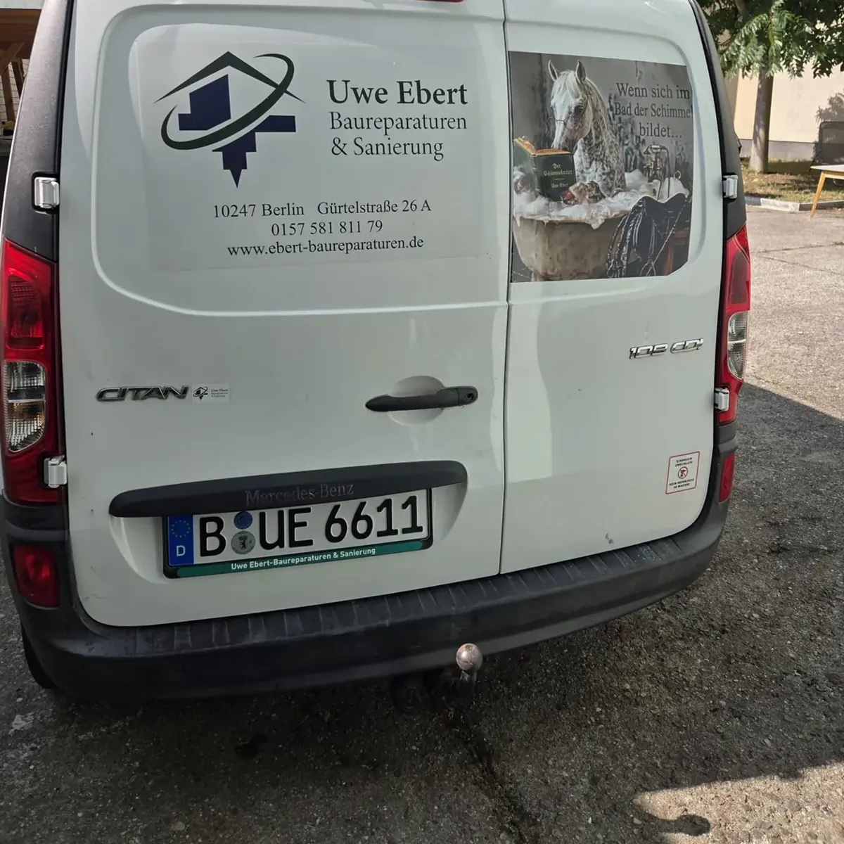 Firmenwagen Citan von Uwe Ebert Baureparaturen und Sanierung in Berlin, Heck mit Logo und Schimmelreiter-Motiv, Kennzeichen B-UE 6611