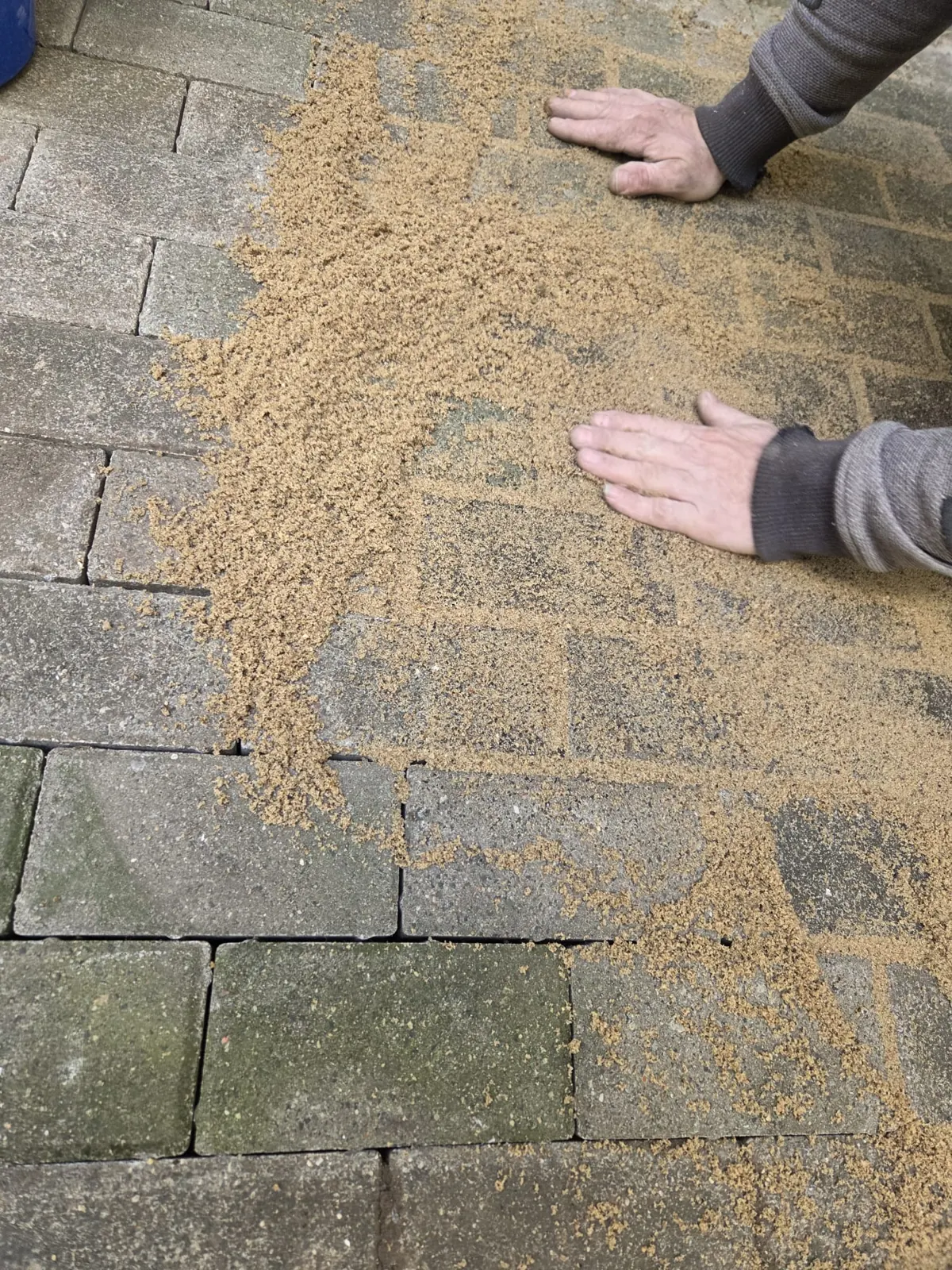 Fugen der neu verlegten Terrasse werden mit Sand eingekehrt