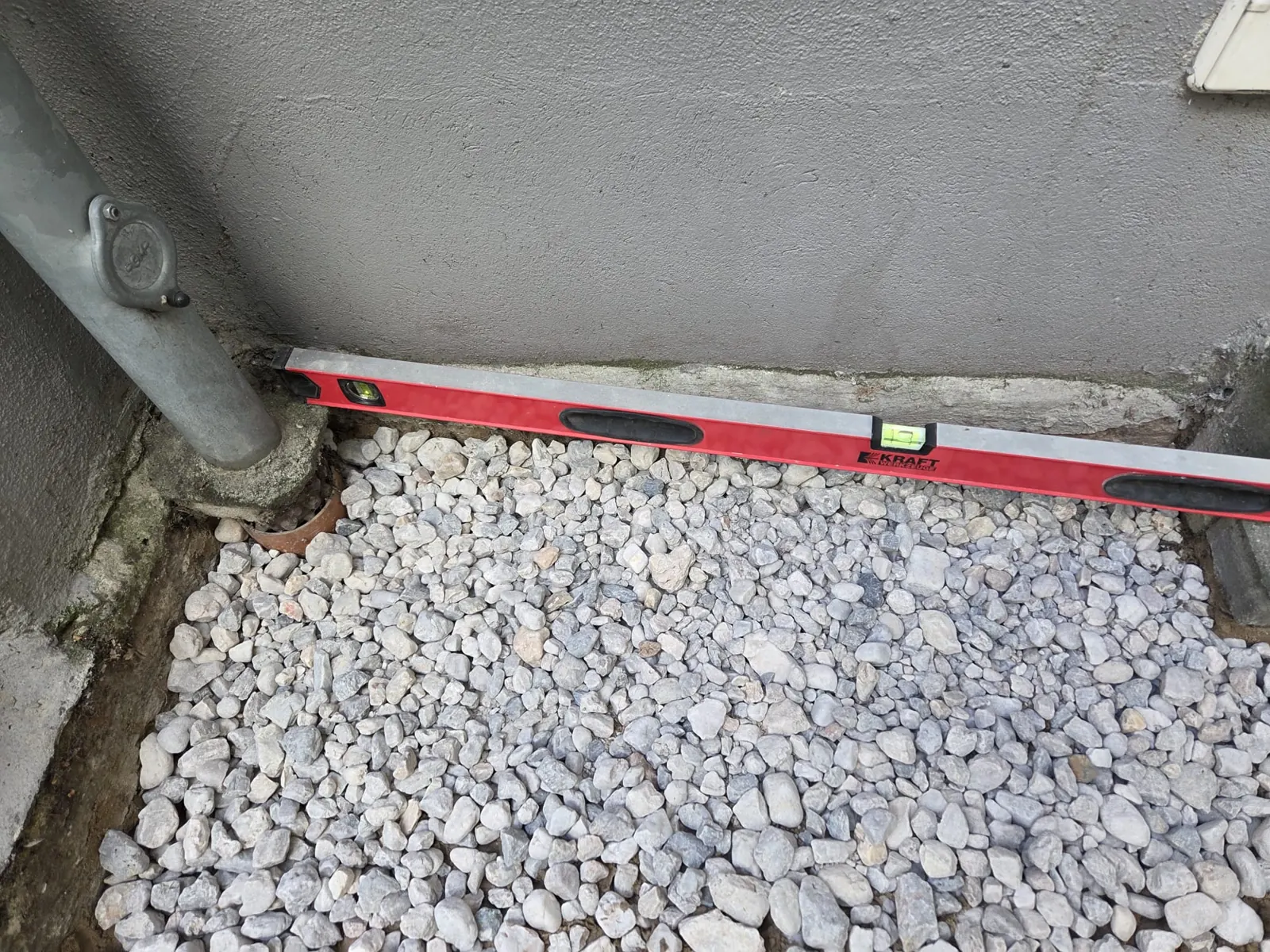 Fertiger Traufstreifen aus Kies an der Hauswand neben dem Fallrohr